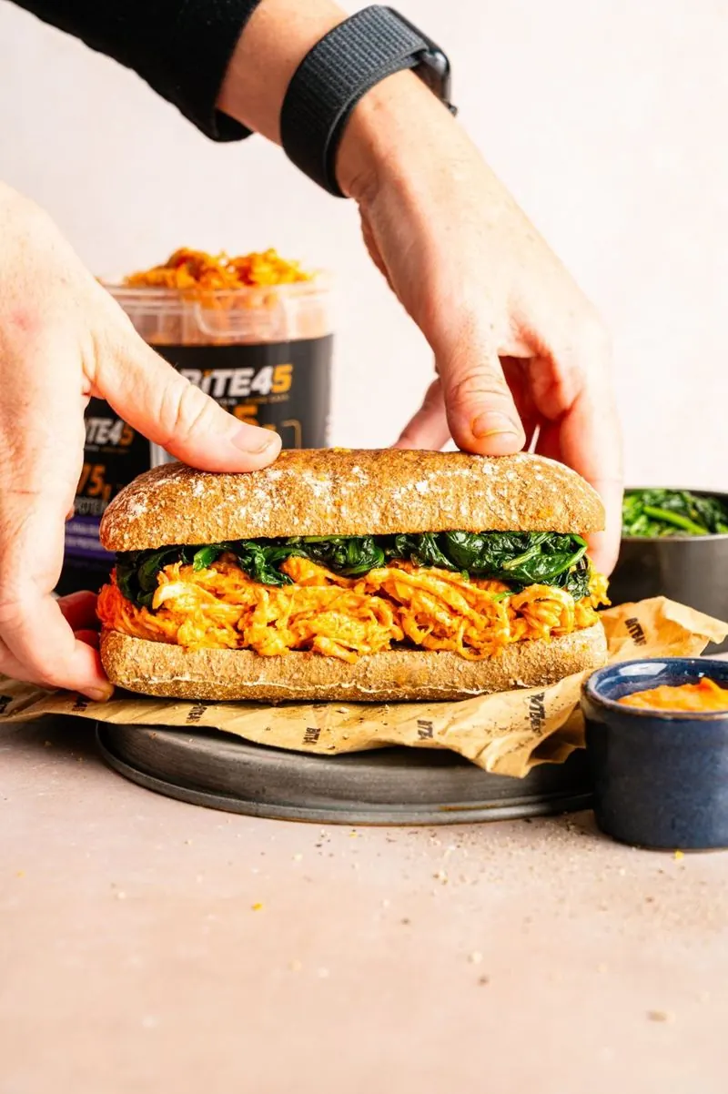 Hands assembling a romesco chicken ciabatta